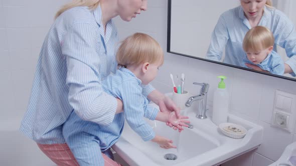 Mother and Her Little Baby Wash Hands and Face in Bathroom