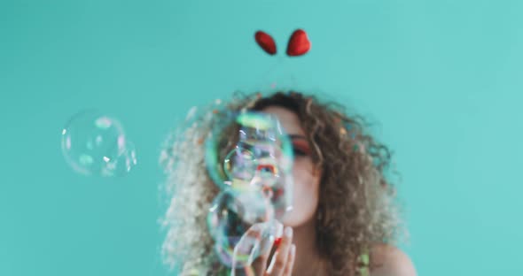 A beautiful curly girl blowing bubble to the camera