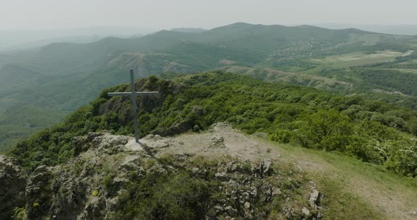 Dreamy scenery of a Christian cross on top of wild, forested hills nearby Kojori.