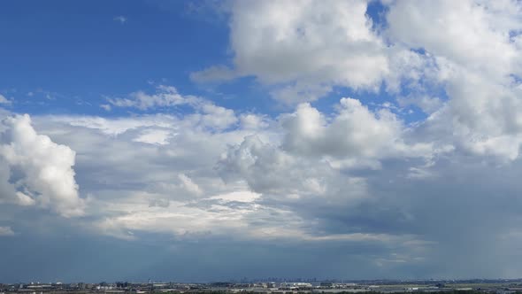 Timelapse of cumulus floating clouds against blue sky with miniature city view. wide shot alt