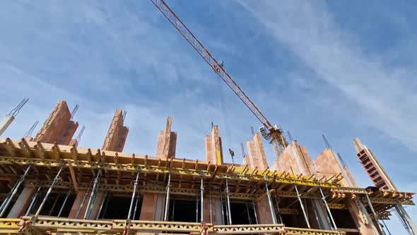 Yellow crane moving and transporting heavy load at construction site in wide-angle shot