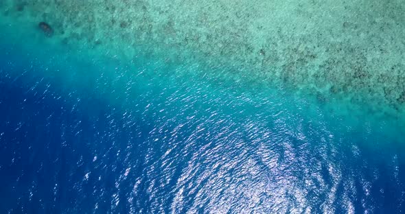 Wide birds eye tourism shot of a paradise sunny white sand beach and aqua blue water background in c