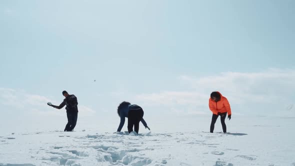 Girls and a Guy Playing Snowballs on a Snowy Field