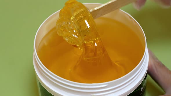 Sugar paste or honey wax for hair removal, dripping from wooden wax sticks - depilation and beauty.