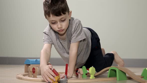 Cute boy plays with a wooden train, takes him across the bridge on flights. Wooden educational toys.