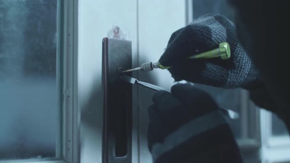 Close Up Of Burglar Holding Lock-Picker To Open A House Door