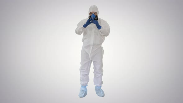 Doctor in Hazmat Protective with Glasses and Respirator Uses Syringe on Gradient Background