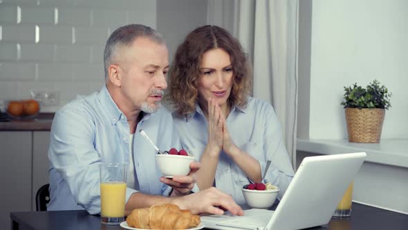 A Married Couple Discusses the News on the Internet on a Laptop