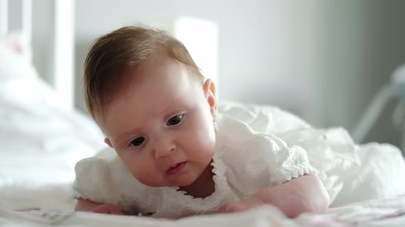 Close Up View of Baby is Lying on the Bed and Smiling at the Camera