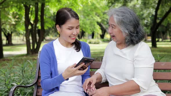 Elderly mother and Asian daughter lounging in the park