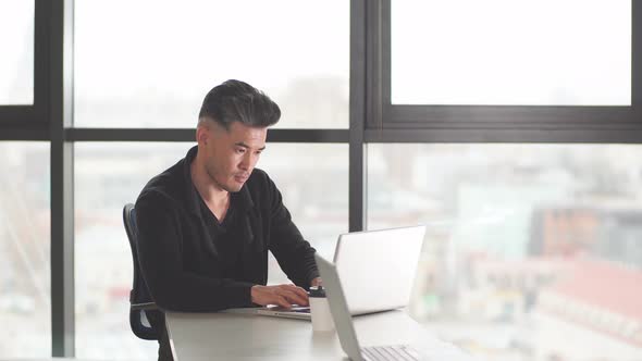 Portrait of Chinese Businessman Sitting at Office Desk Using Computer