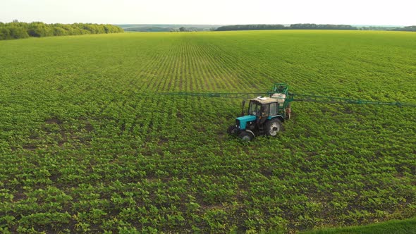 Aerial View of Farming Tractor Spraying on Field with Sprayer Herbicides and Pesticides at Sunset