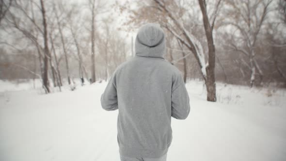 Rear View of a Man Running in Park Winter Under Snowfall