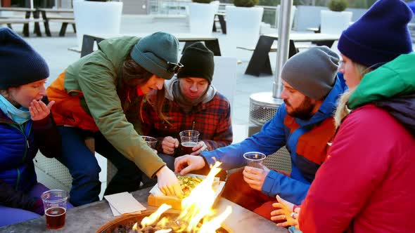 Friends having snacks near campfire