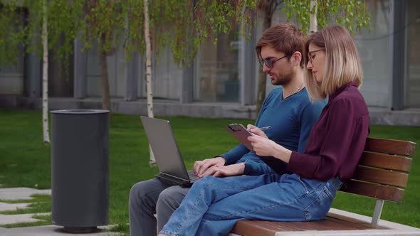 Two professional coworkers discuss concentrating typing on laptop