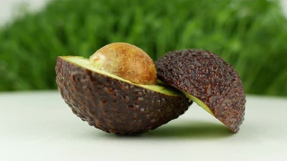 Avocado rotates on a green grass background. 4K video close-up of wholesome and healthy food.