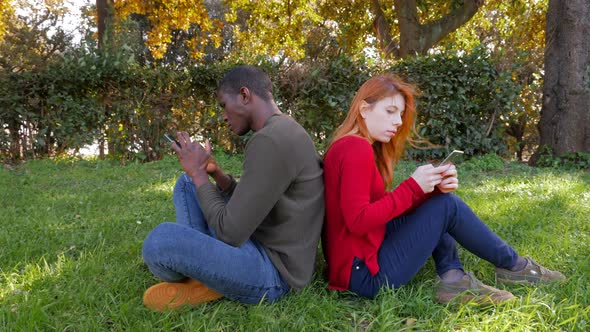 Mixed race friends using smartphones on lawn .youth incommunicability.