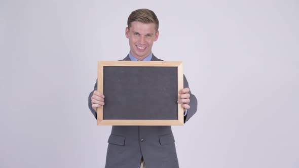 Happy Young Handsome Businessman Holding Blackboard and Giving Thumbs Up