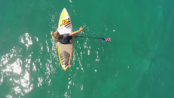 Aerial view of a man sup stand-up paddleboard surfing in Hawaii