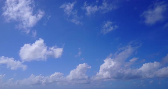 Wide fly over abstract shot of a white sandy paradise beach and aqua turquoise water background in 4