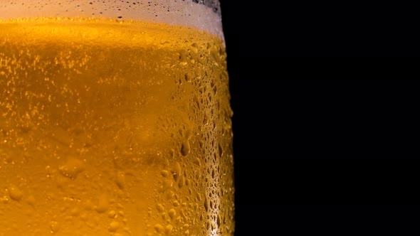 Cold Light Beer in a Glass with Water Drops Rotates