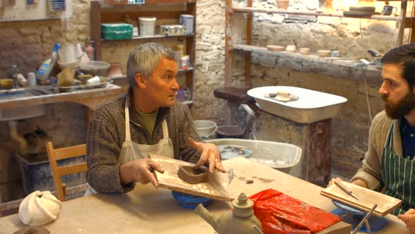 Potter teaching his colleague to mold the clay