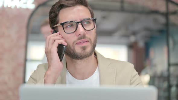 Close Up of Man with Laptop Talking on Smartphone