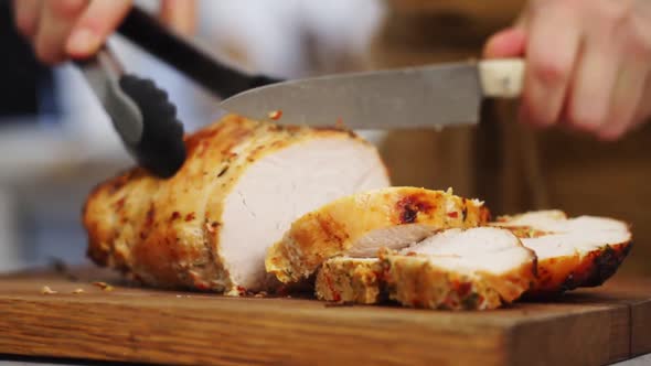 Crop chef cutting appetizing roasted chicken in kitchen