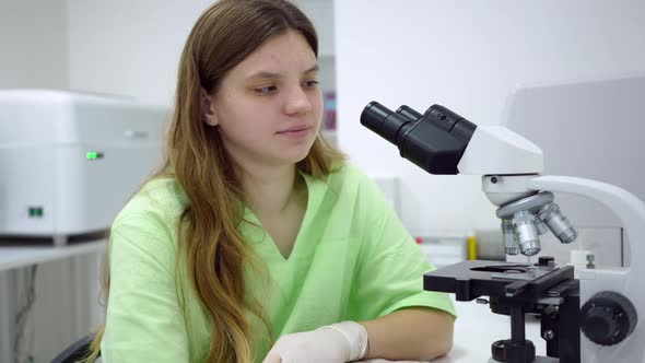 Portrait of Expert Young Lab Assistant Posing at Microscope Indoors Smiling