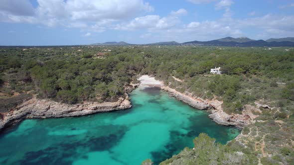 Flying over turquoise water towards the white sandy beach  of Cala Sa Nau