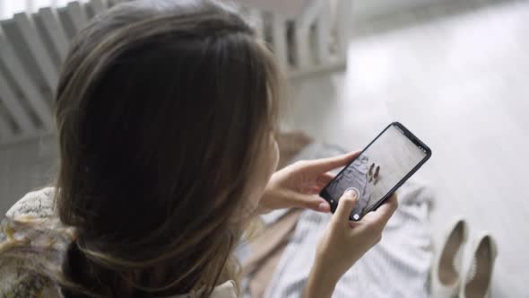 Brunette Holds Black Smartphone and Makes Photos of Clothes