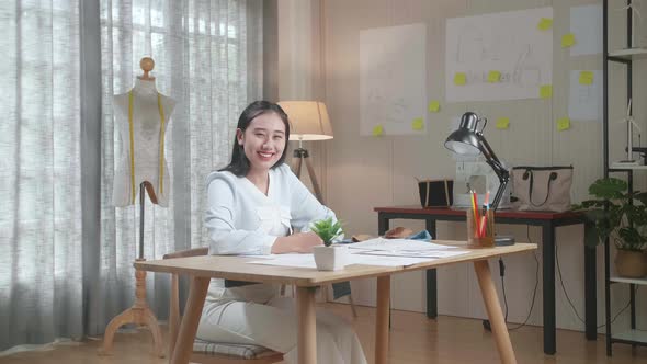 Asian Woman Designer With Layout Bond Smile To Camera While Working With Laptop At The Office