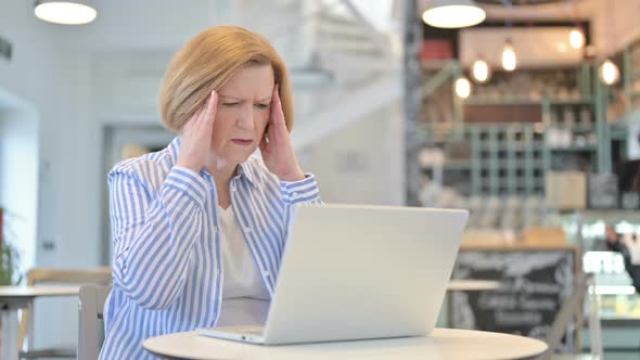 Laptop Use By Creative Old Woman with Headache in Cafe