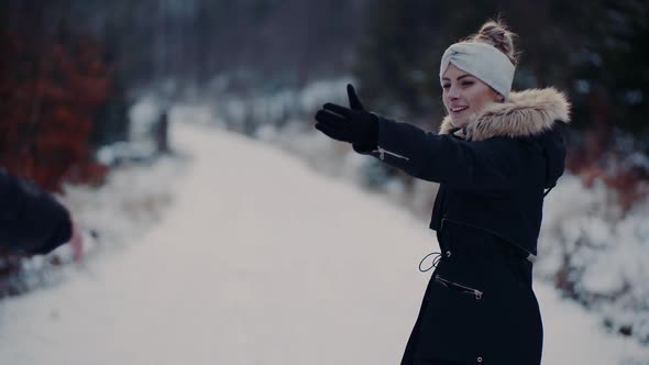 Woman Giving Hand To Boyfriend Ona Walk in Forest in Winter