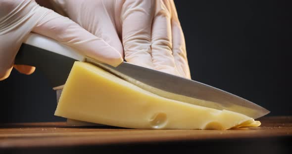 Chef Cuts Cheese with Large Holes Into Long Sticks on Board