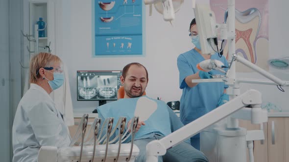 Patient Holding Mirror to See Teeth Alignment After Dental Procedure