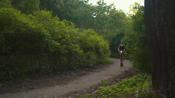 Revealing Shot Confident Fit Woman Rides Her Electric Scooter and Stops at a Beautiful Evening Park