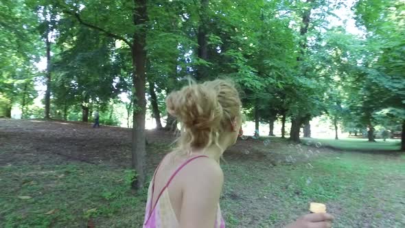 young woman blonde air playing with bubblesoap in a city park.