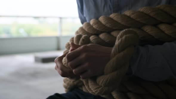 Closeup of Businessman Hand in Shirt Tied with Thick Rope in Parking Lot