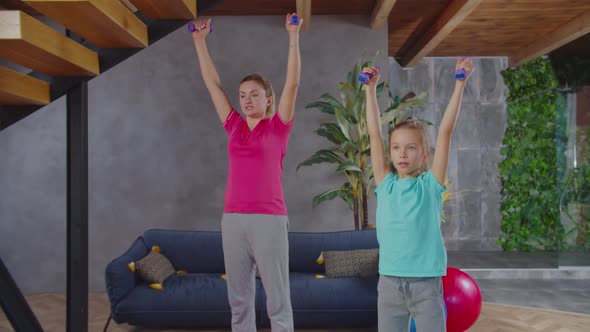 Mom and Daughter Exercising with Dumbbells at Home