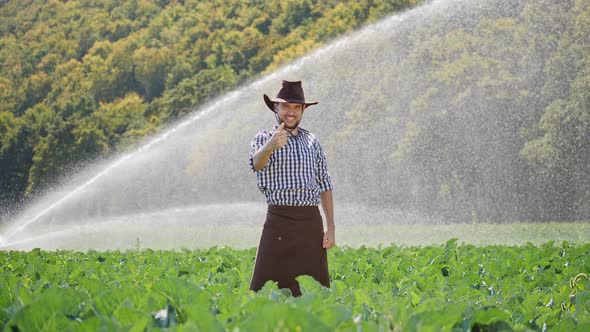 Rarmer Standing in Plantation and Raises Hands Up. Happy Farmer Enjoying Success