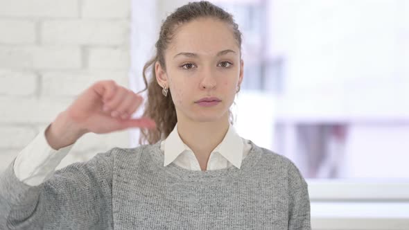 Portrait of Disappointed Young Latin Woman Doing Thumbs Down in Office 