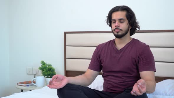 An Indian young adult doing meditation and yoga in a bedroom