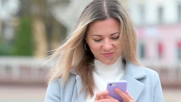 Portrait of happy girl Using Mobile Phon on city street.
