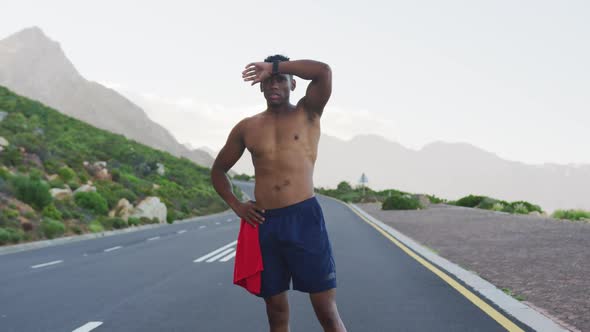 African american man standing and flexing his muscles on a coastal road