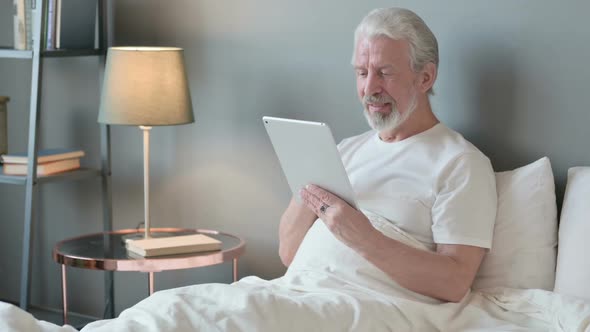 Online Video Chat on Tablet By Old Man in Bed