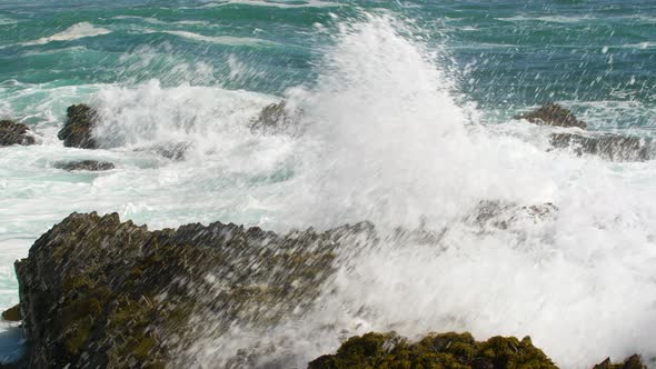 Ocean Waves crashing on rocks with blue sea in background (SLOWMO)