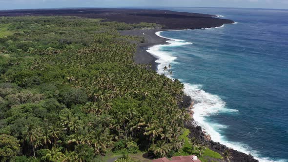 Aerial descending and tilting up shot of a brand new black sand beach along the coast of the Big Isl