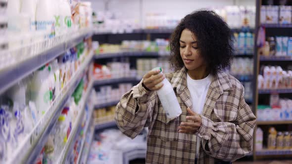 Black Woman Doing Grocery Shopping in Supermarket Looking at Full Shelves Buying Food