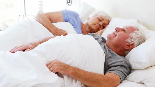 Senior couple sleeping on bed in bedroom